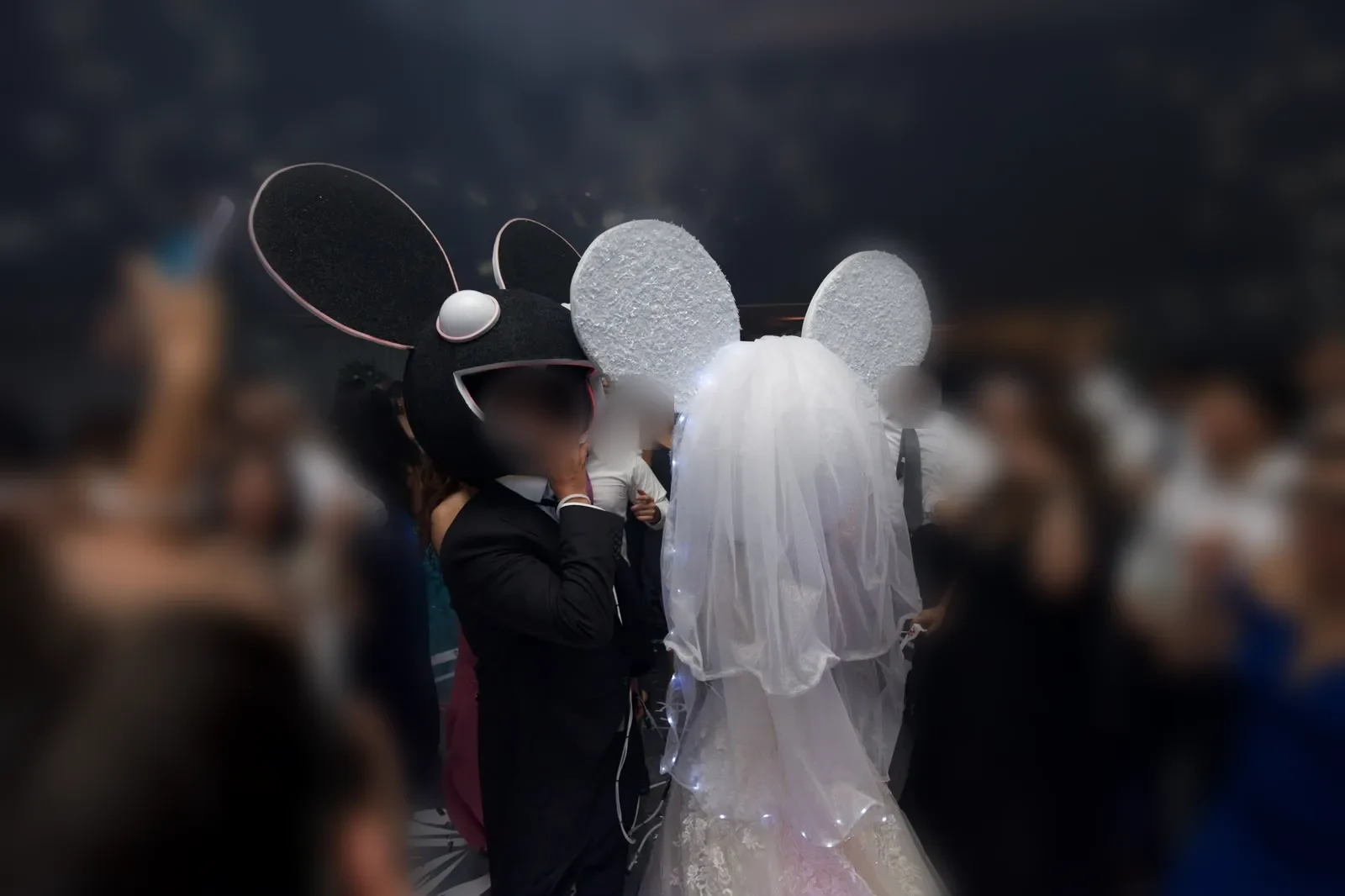 Los novios con cabezas LED rodeados de invitados en la pista